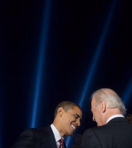 Barack Obama and Joe Biden smiling at each other on stage