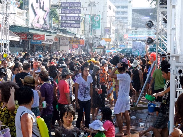Dense crowd on a street during Songkran, people soaked with water and carrying buckets and water guns
